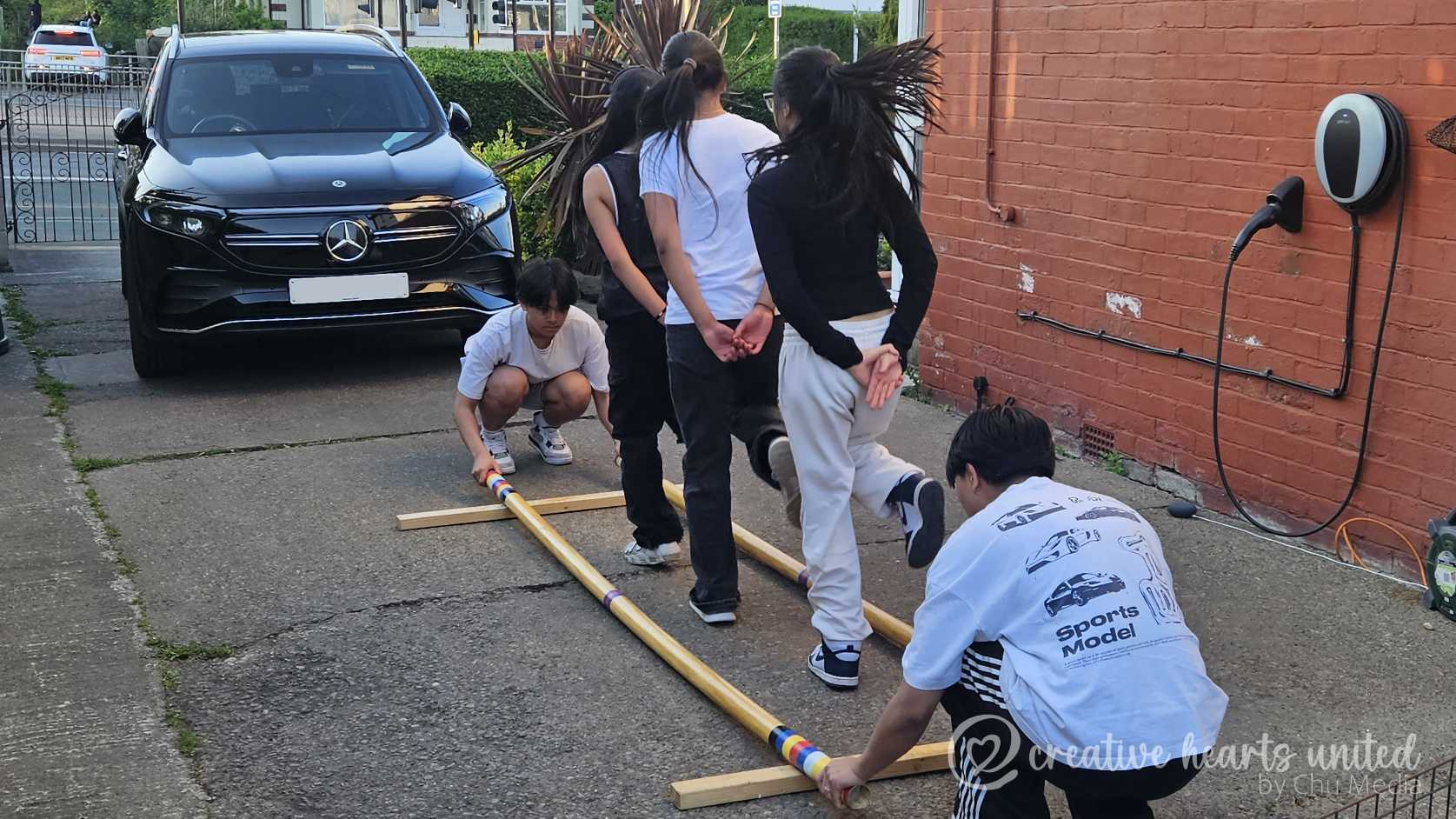 Creative Hearst United - British- Filipino teens rehearsing Tinikling at a driveway